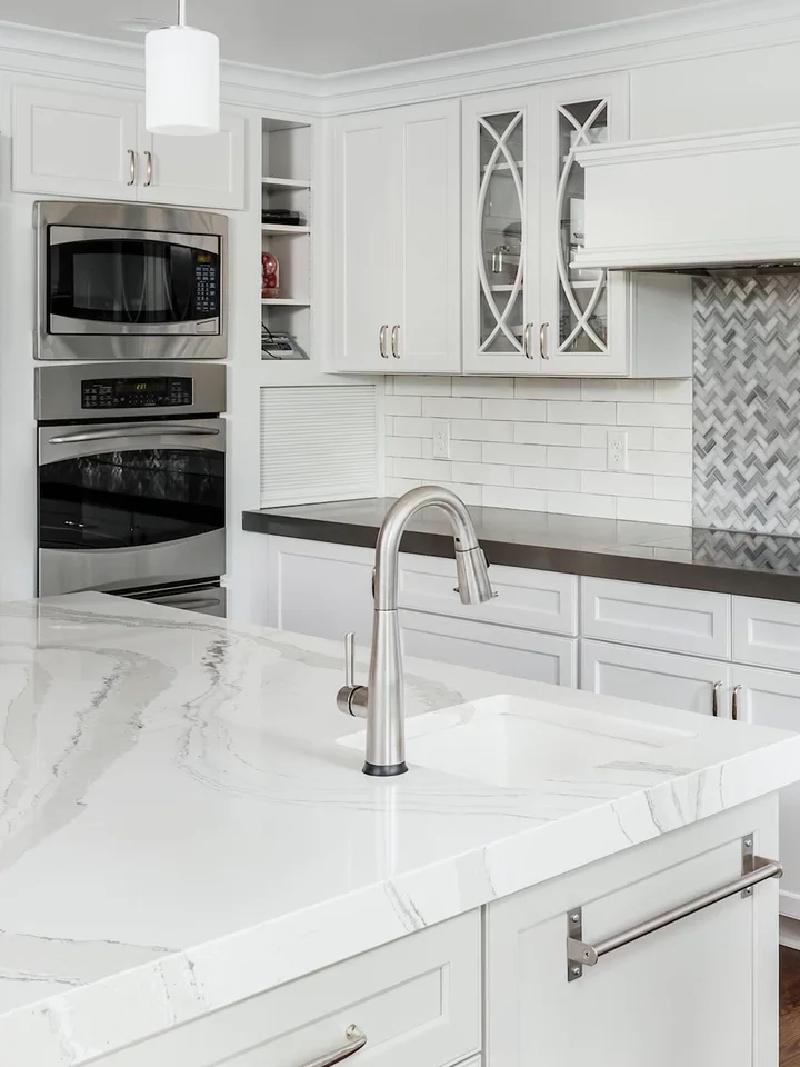 A white kitchen with a marble island and full-height backsplash