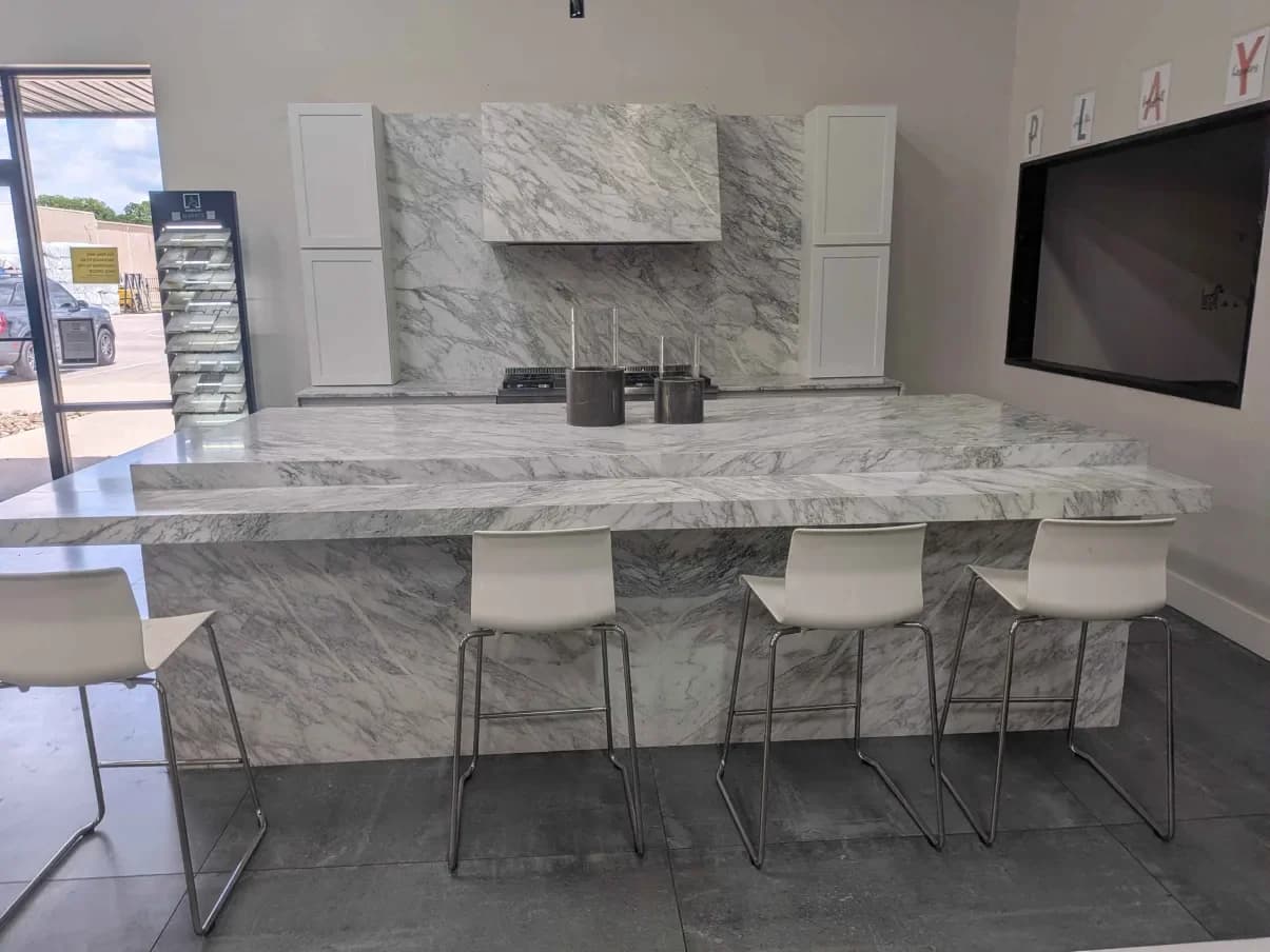 A showroom kitchen built in white marble: island, countertops and a full-height backsplash