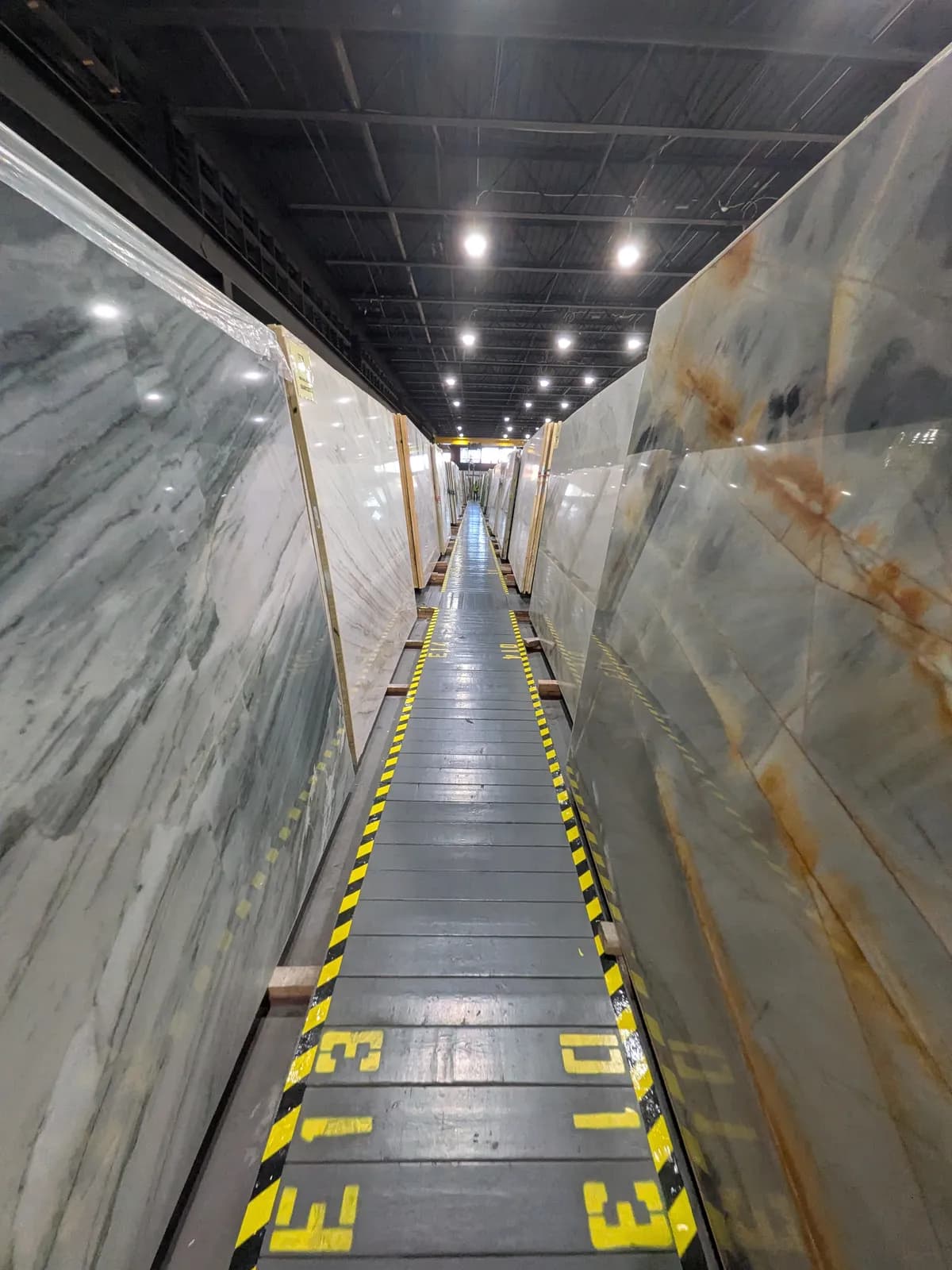 An aisle of slabs with rack numbers painted in yellow on the floor