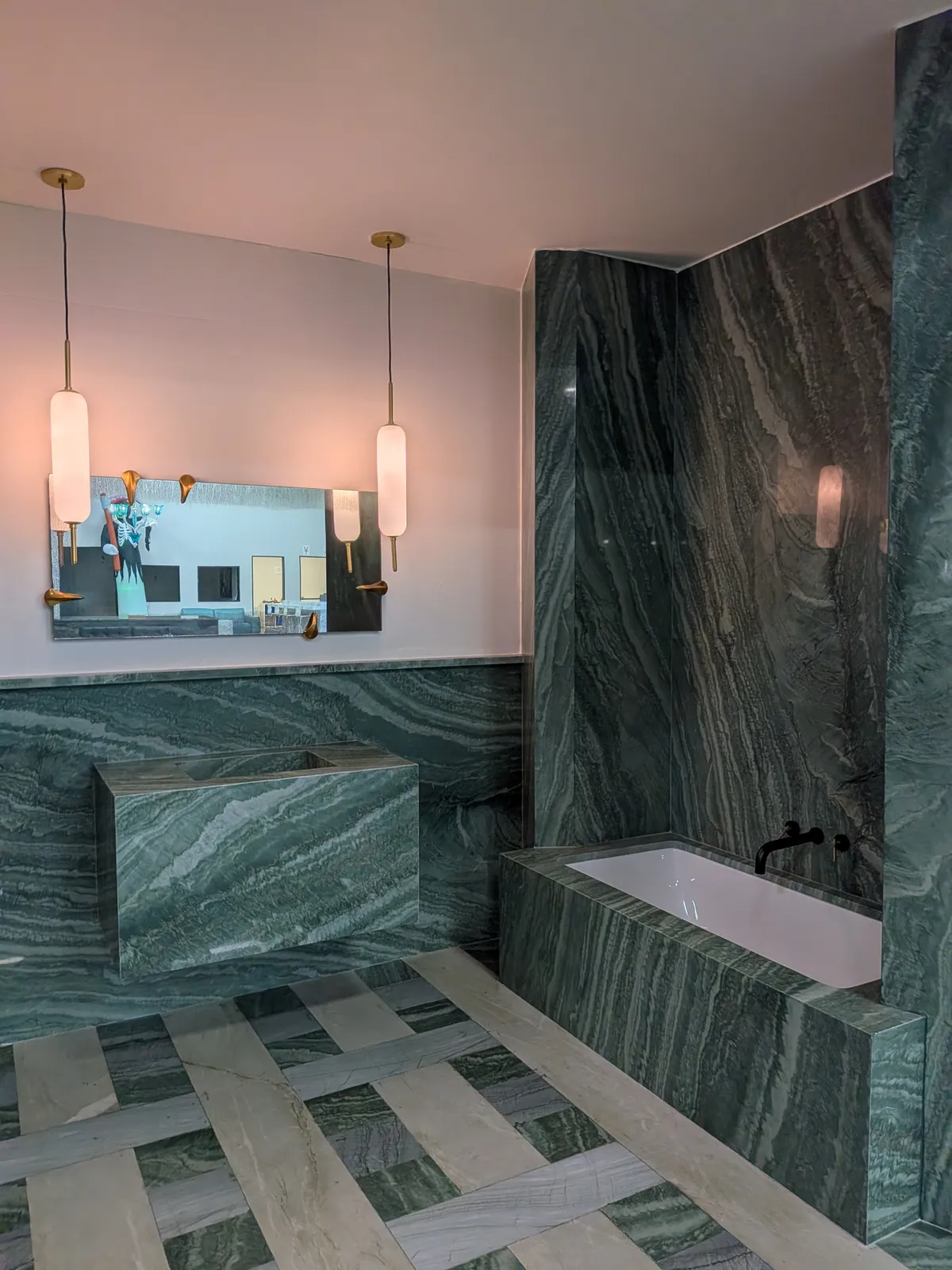 A bath set in green veined stone, with pendant lights over the vanity